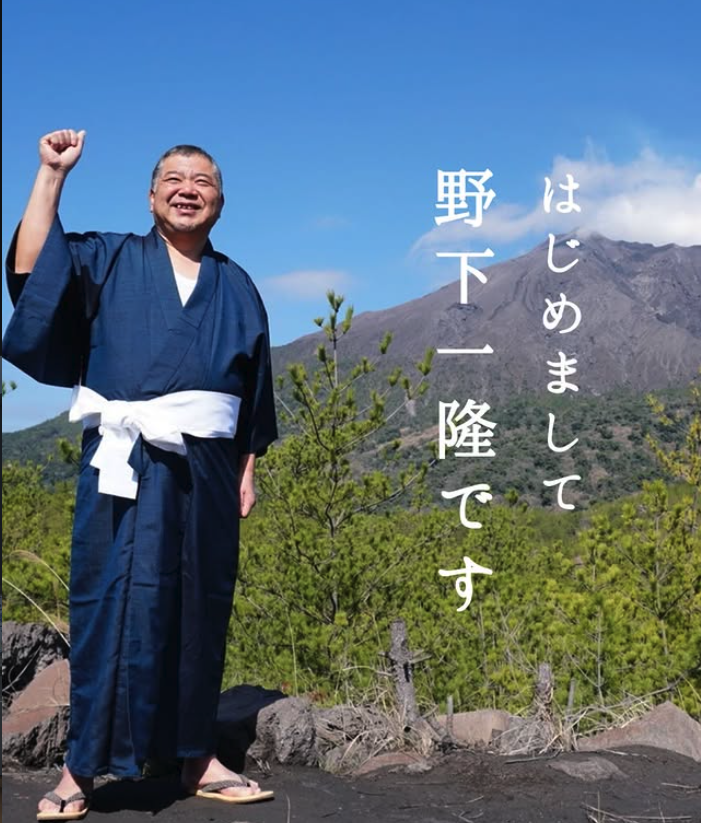 桜島を背に立つ有限会社ホームガイド代表 野下一隆